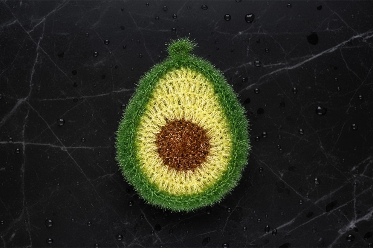 Crocheted avocado dish scrubber on a textured black background