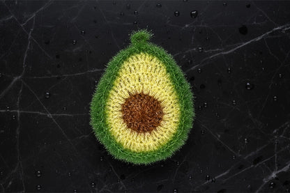 Crocheted avocado dish scrubber on a textured black background