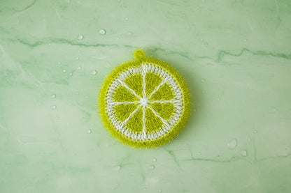 Crocheted green lime dish scrubber on a green textured background.
