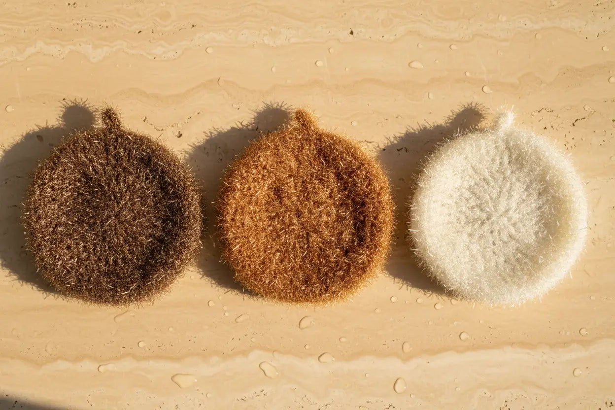 Three scrubbies on a warm travertine surface