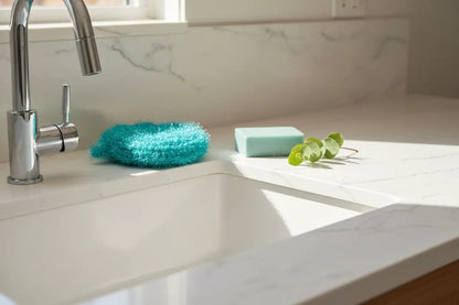 Kitchen sink with turquoise scrubby and soap bar on a marble countertop