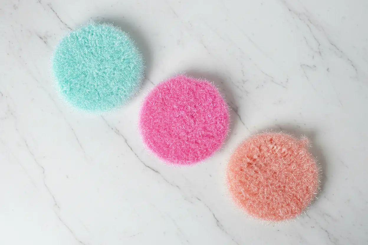 Three colorful scrubbies on a marble surface