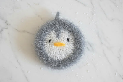 Gray penguin-shaped dish scrubber on a white marble surface