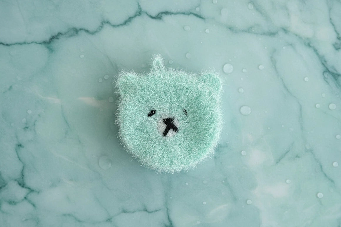 Light minty fuzzy bear dish scrubber on a marble surface