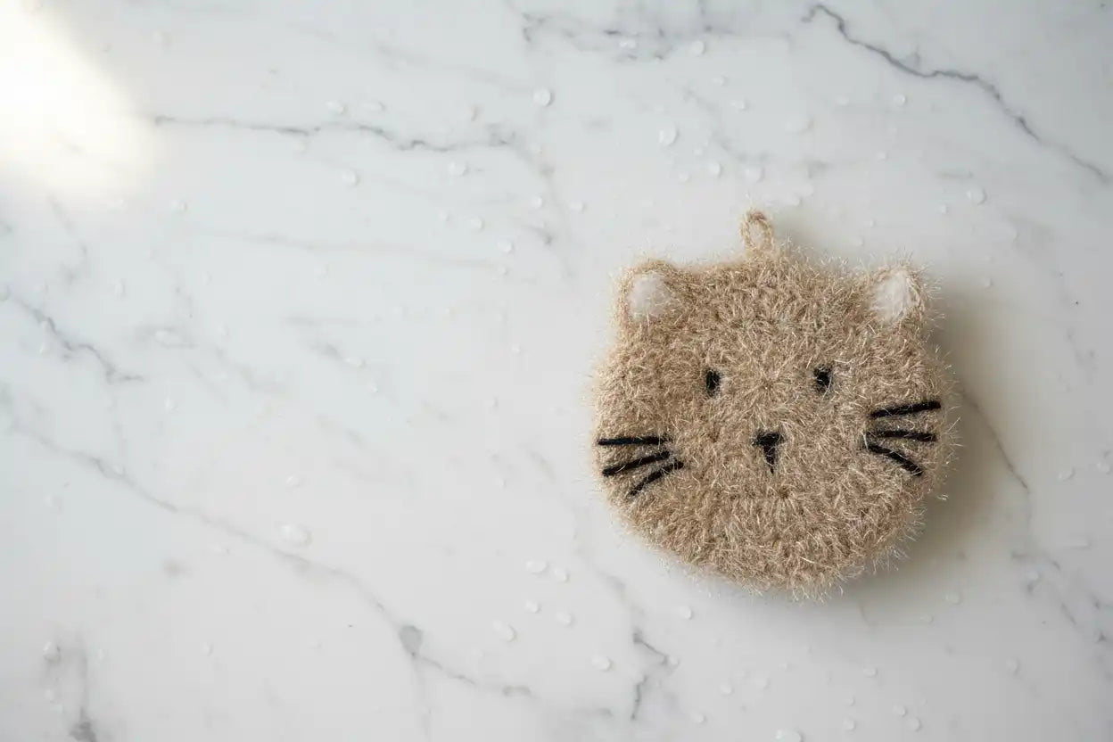 Cat-shaped dish scrubber on a marble surface
