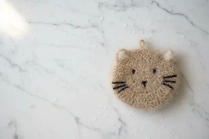 Cat-shaped dish scrubber on a marble surface
