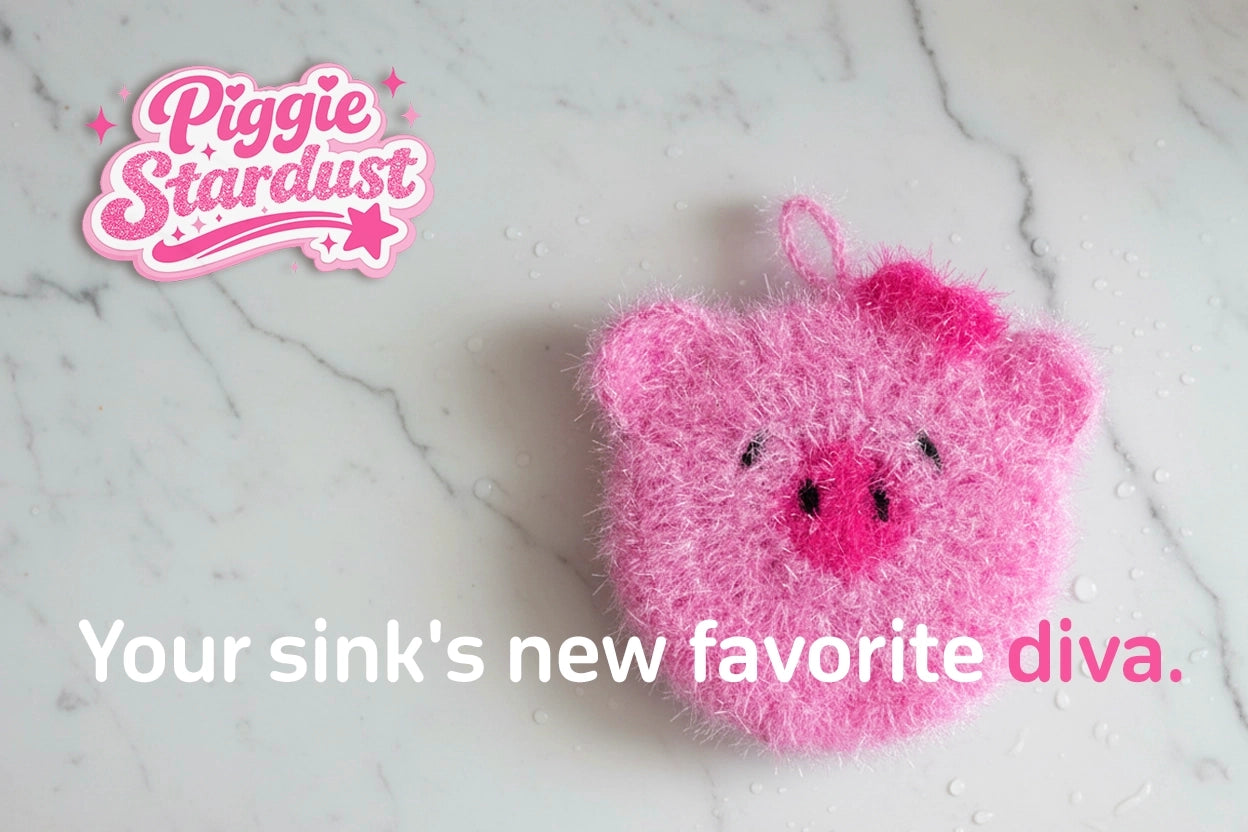Pink crocheted pig dish scrubber on a marble surface, branded 'Piggie Stardust'.