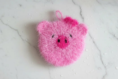 Cute pink pig dish scrubber on a white marble surface