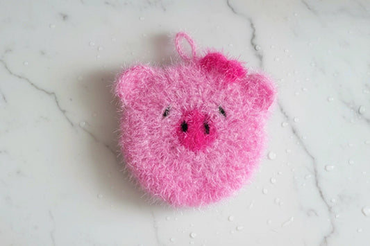 Cute pink pig dish scrubber on a white marble surface
