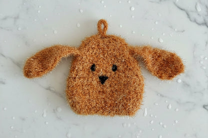 Rufus — brown long-eared fuzzy dog dish scrubber on a white marble surface