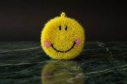 Yellow smiley face dish scrubber on a dark surface